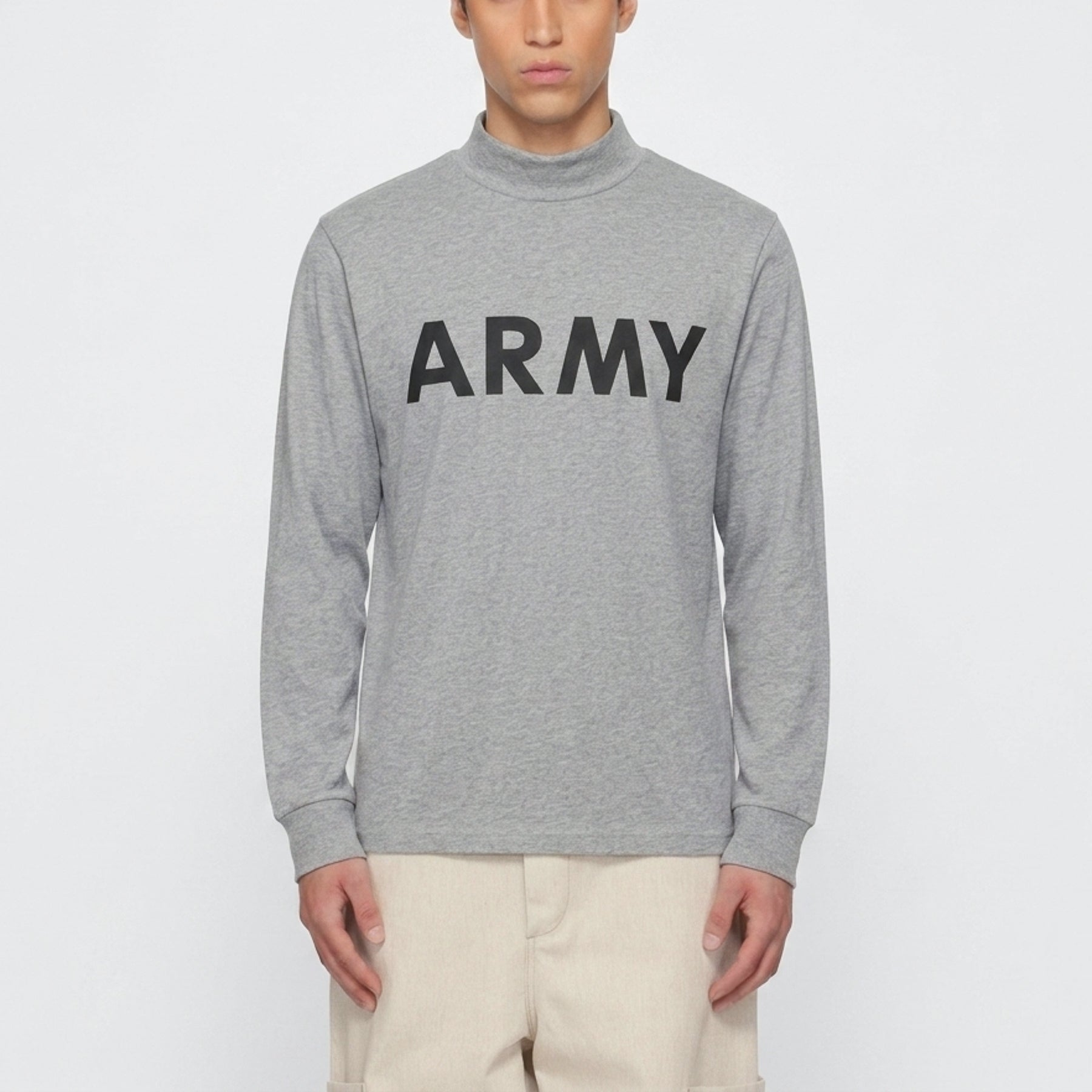 A man wearing a heather gray long-sleeve mock neck sweatshirt with the word 'ARMY' printed in bold black letters across the chest, paired with beige pants, against a plain light gray background.