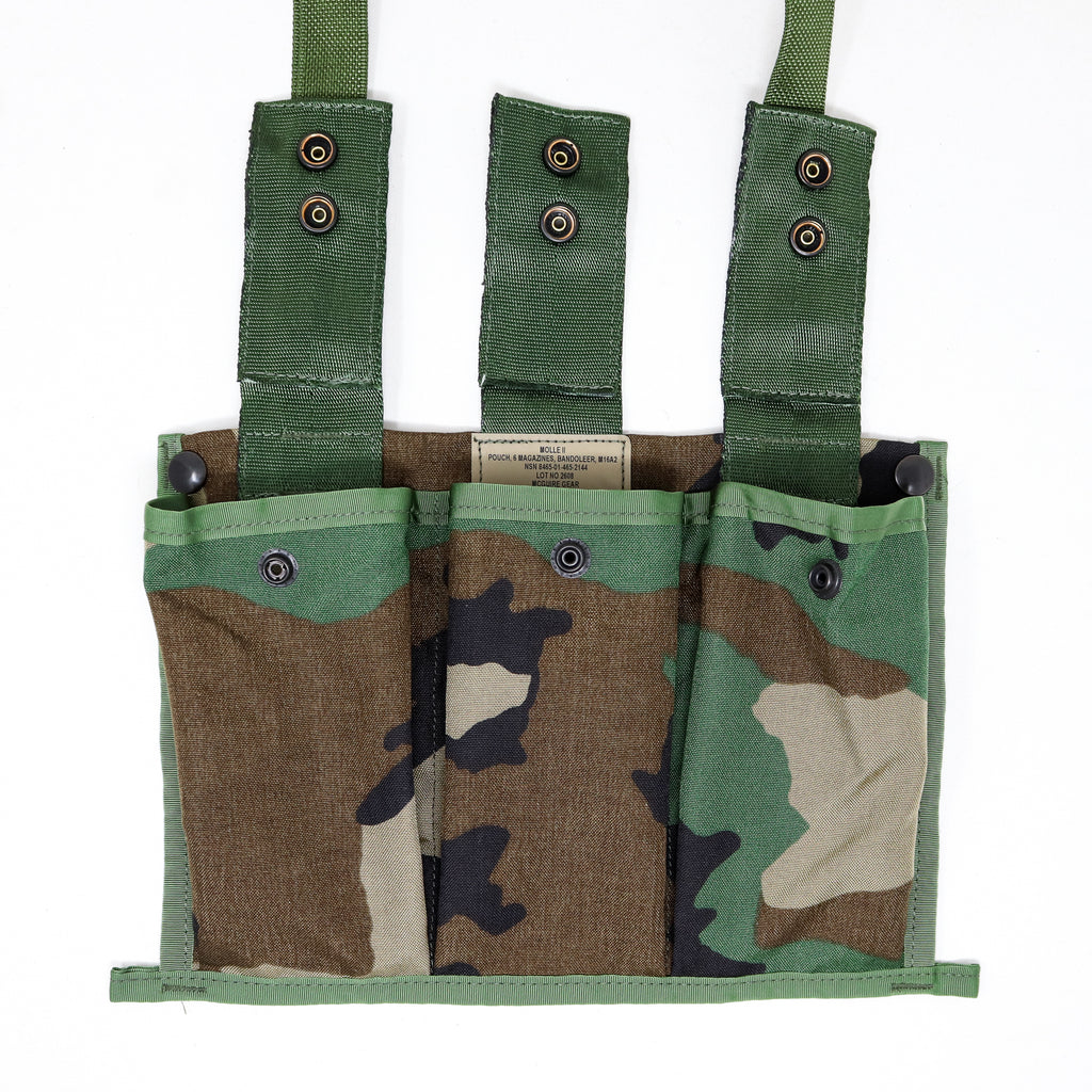 A military-style fabric pouch with three vertical pockets and three green webbing straps, shown on a plain white background. The pouch features a woodland camouflage pattern in green, brown, black, and tan.